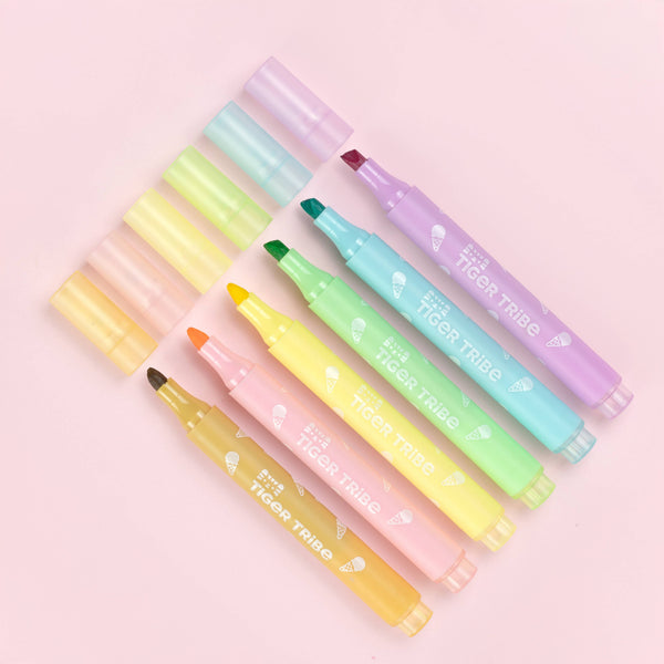 Set of colorful highlighters with visible brand name on a pink background