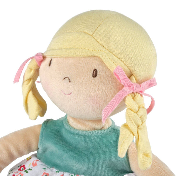 Toy doll with blonde hair, pink ribbons, and a green dress on a white background