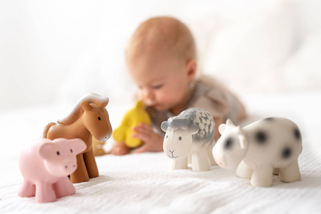 Child playing with animal figurines on a white surface