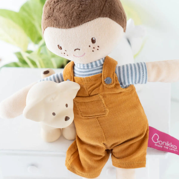 Stuffed toy with a baby doll wearing a brown outfit and a small white bear plush toy on a white background.