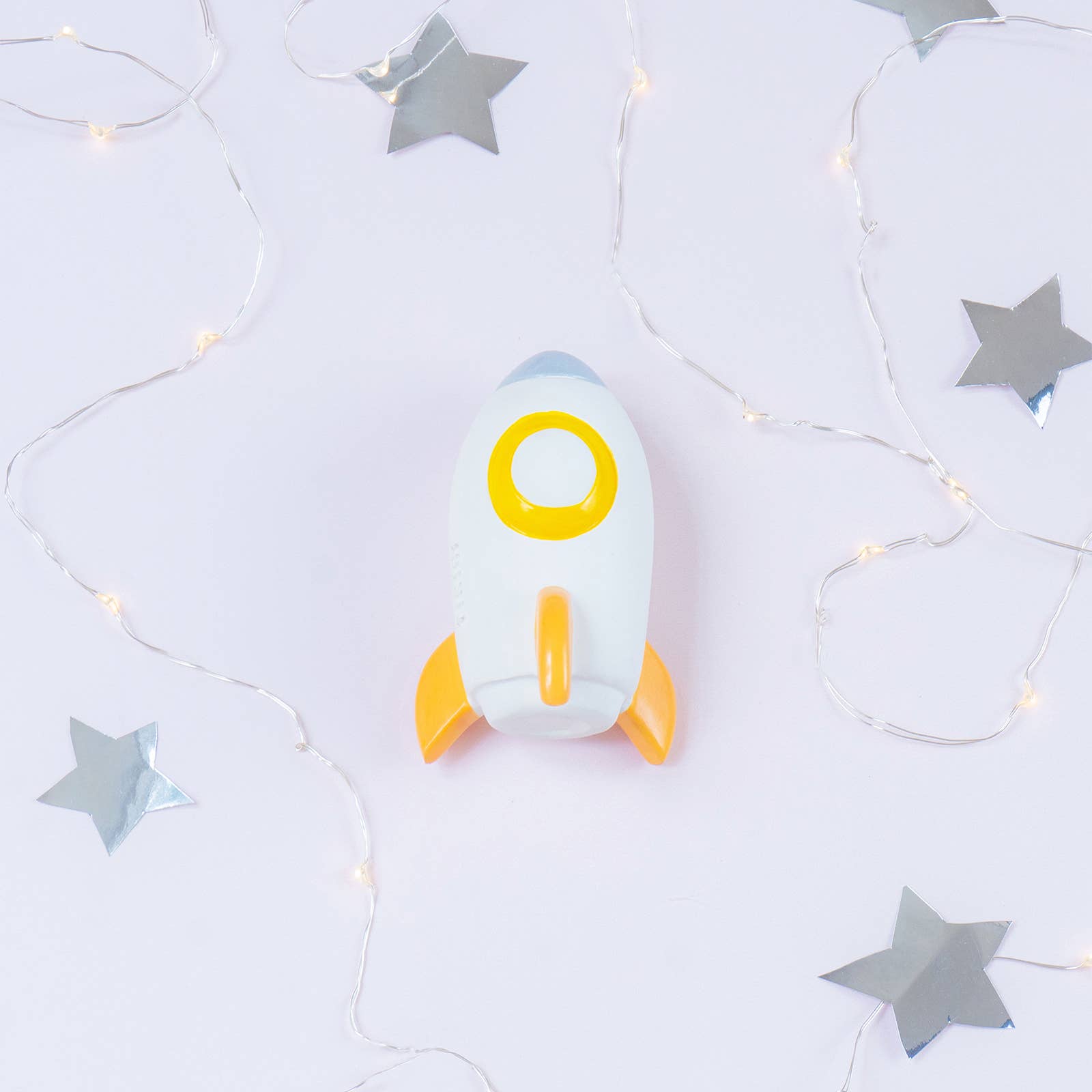 Toy rocket ship with a yellow circle on a light gray background with star decorations
