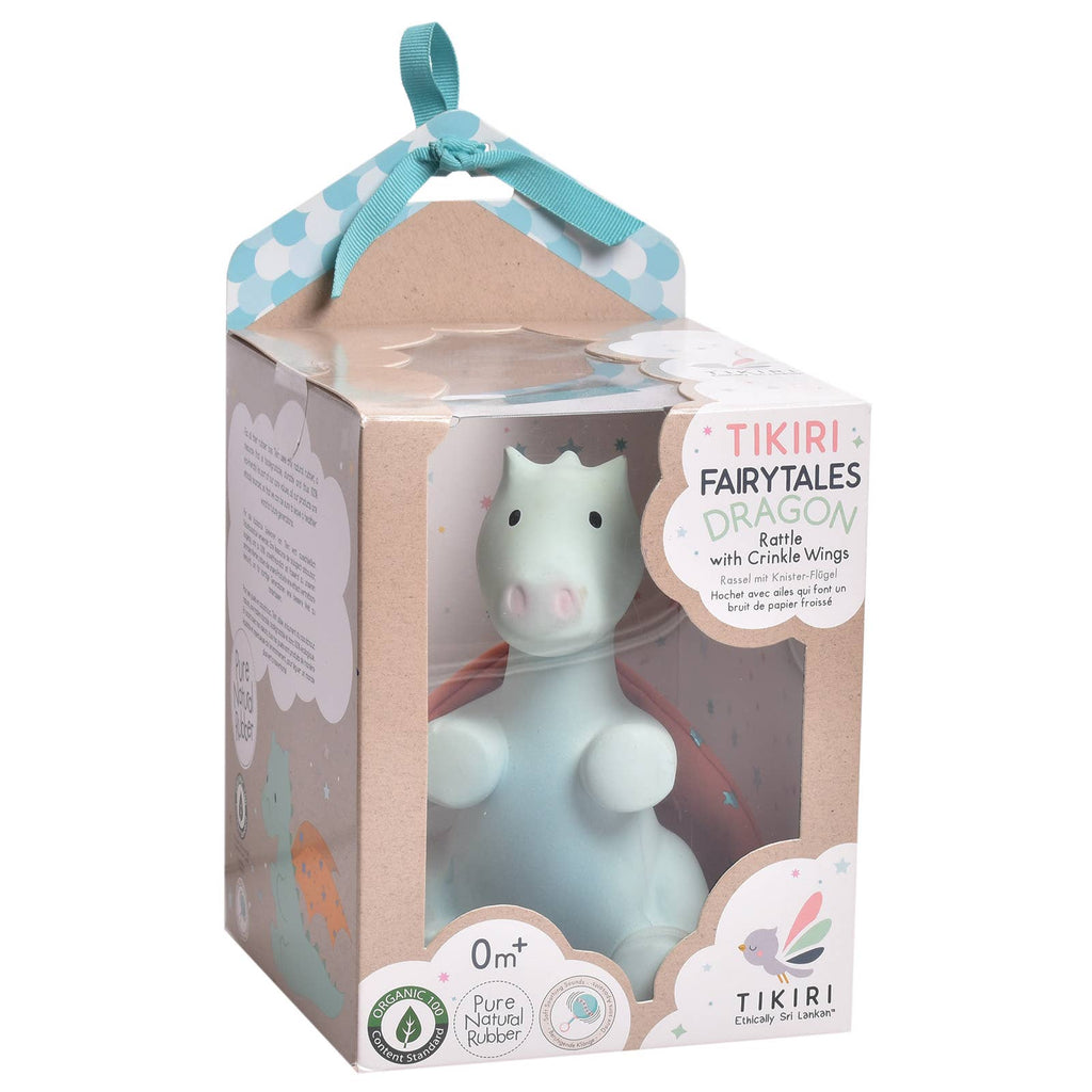 Tikiri Fairytales Dragon Eartie with Crinkle Wings, shown in its original retail packaging. The product is a light blue dragon figurine with pink wings and a pink nose, visible through a clear window in a brown cardboard box with a light blue polka-dot ribbon handle.