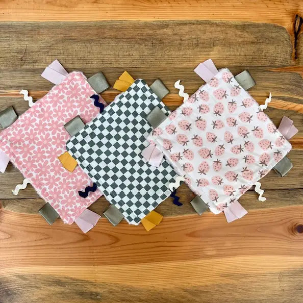 Three fabric tags with different patterns on a wooden surface