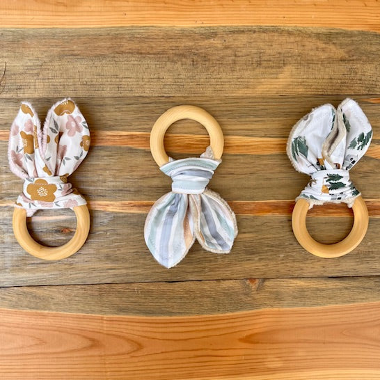 Three wooden teething rings with fabric covers on a wooden surface