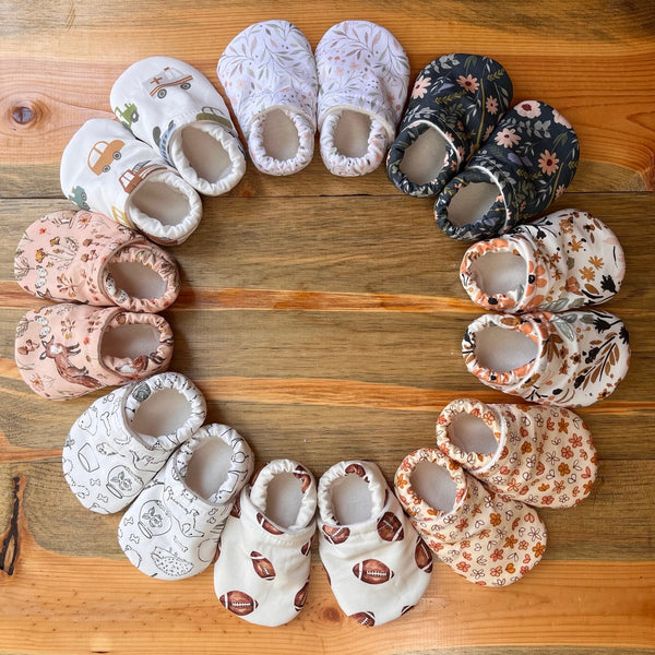 Assorted baby shoes arranged in a circular pattern on a wooden surface