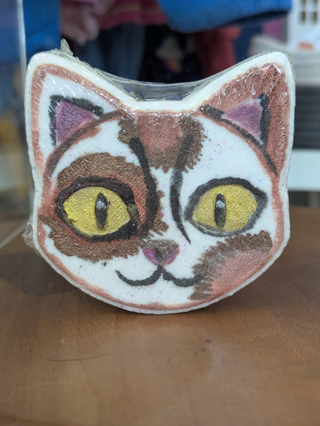 Cat-shaped bath bomb with a face on a wooden surface