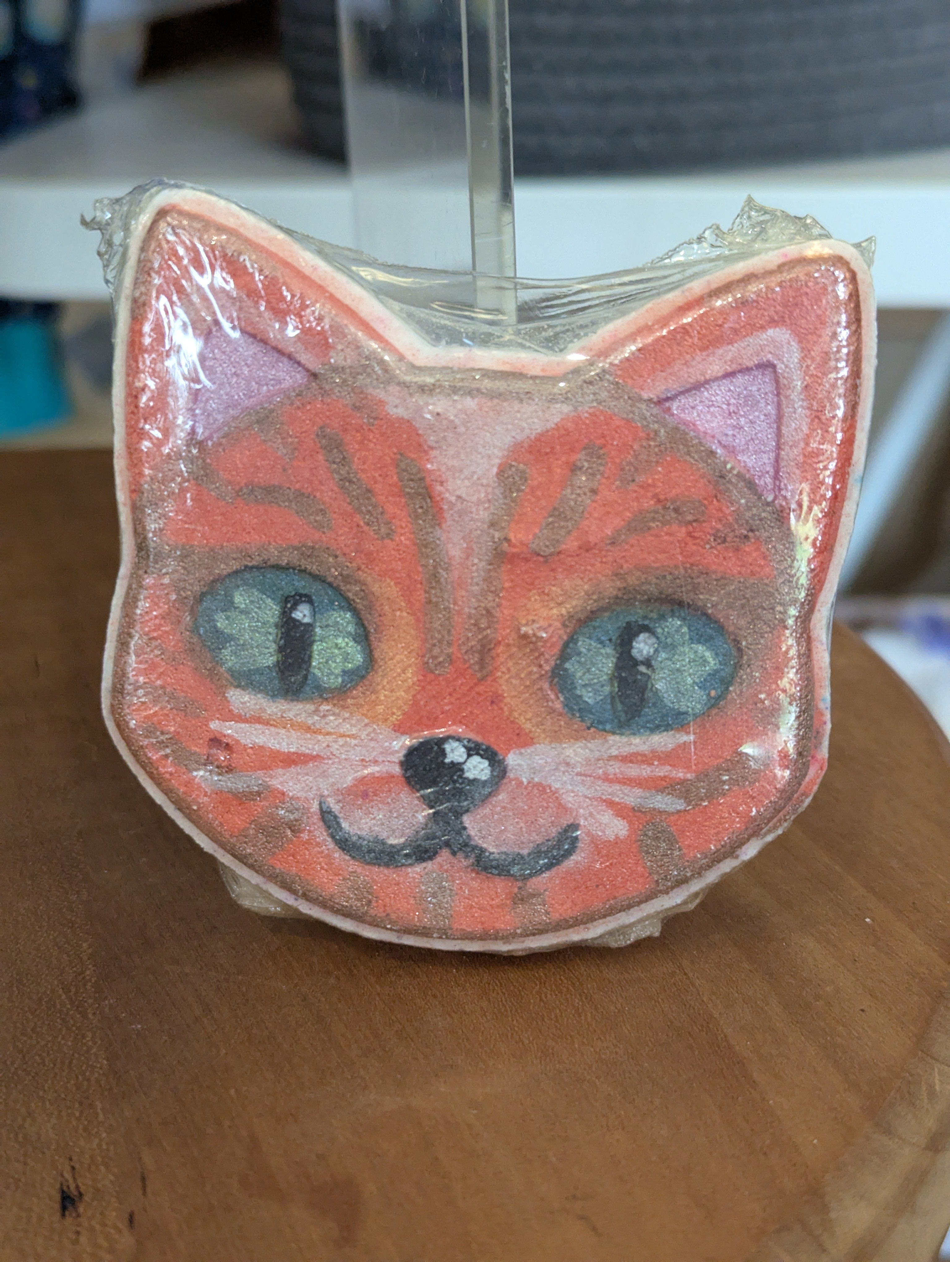 Cat-shaped bath bomb with a face on a wooden surface