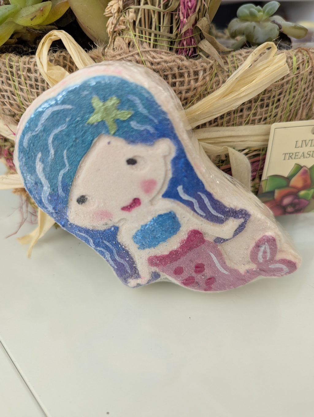 Bath bomb with a mermaid design on a white surface