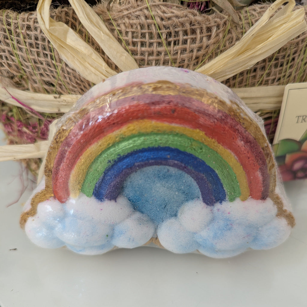 Colorful rainbow-shaped bath bomb on a white surface with a woven basket in the background.