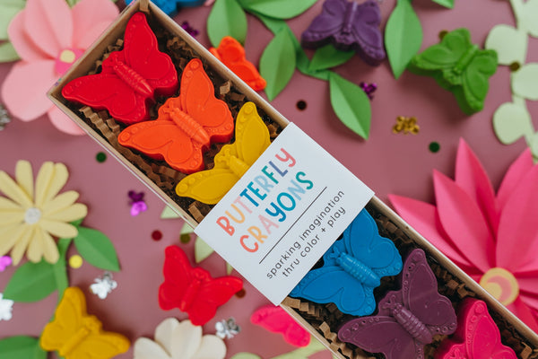Butterfly crayons in a box with colorful butterfly-shaped markers on a floral background.