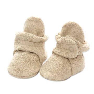 Pair of beige baby booties with fluffy texture on a white background