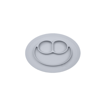 A gray ezpz Mini Mat, an all-in-one placemat and plate designed for mealtime, suctioning to a table surface.