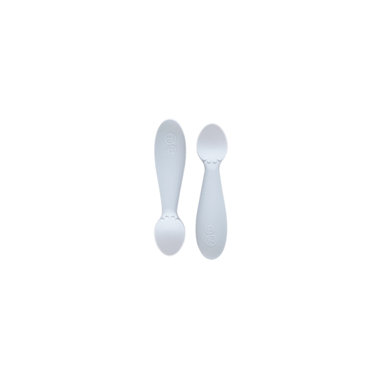 Two white silicone spoons designed for babies, with wide handles and narrow bowls.